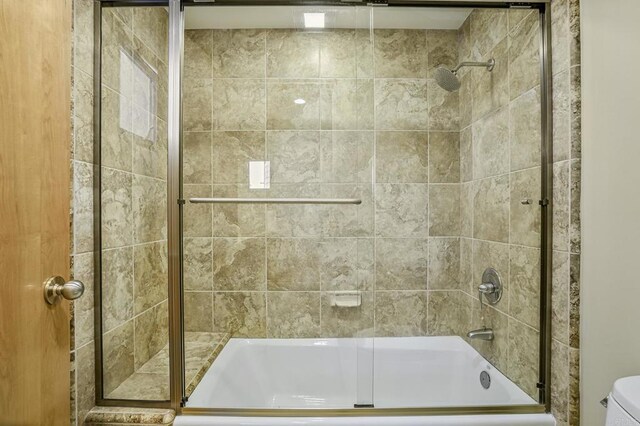 bathroom featuring bath / shower combo with glass door and toilet