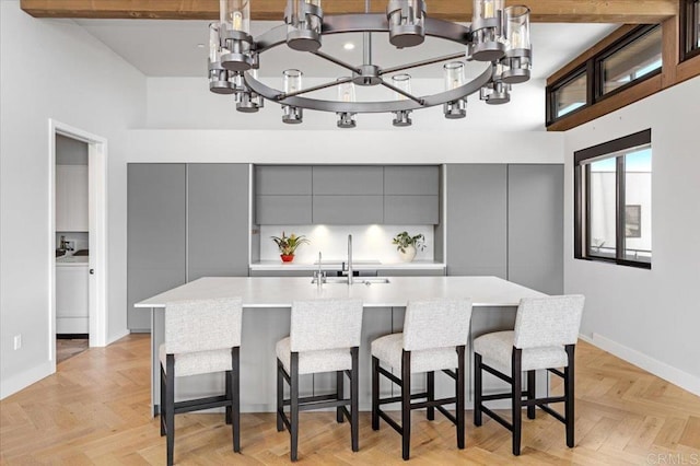 2677 State St # 301, Carlsbad, CA 92008 - kitchen with gray cabinets, modern cabinets, a towering ceiling, light countertops, and a chandelier
