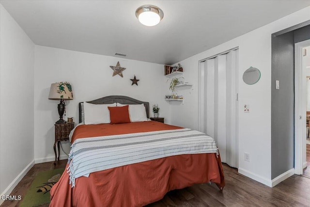 bedroom with visible vents, baseboards, a closet, and wood finished floors