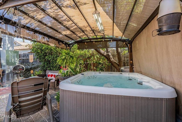 view of patio / terrace with a hot tub and fence
