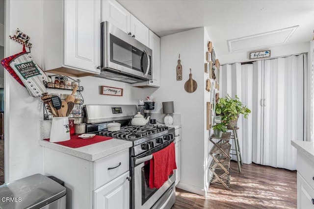 kitchen with light countertops, wood finished floors, white cabinets, and appliances with stainless steel finishes