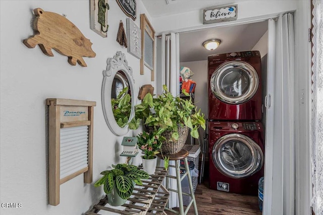 clothes washing area featuring wood finished floors, stacked washer / dryer, and laundry area