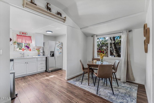 dining room with baseboards, vaulted ceiling, and light wood finished floors