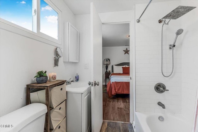 ensuite bathroom featuring toilet, vanity, wood finished floors, washtub / shower combination, and ensuite bathroom