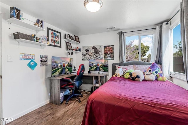 bedroom with baseboards, visible vents, and wood finished floors