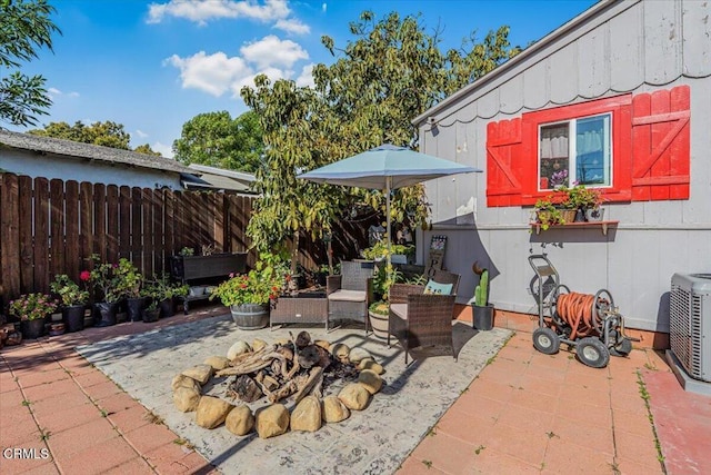 view of patio featuring an outdoor fire pit, cooling unit, and fence