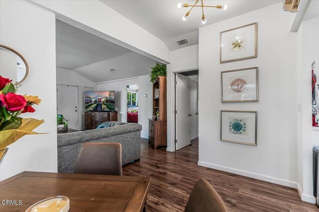 living area with visible vents, baseboards, wood finished floors, lofted ceiling, and a notable chandelier