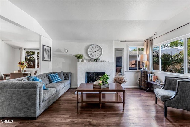 living room with vaulted ceiling, a fireplace, a textured ceiling, dark wood-style floors, and baseboards