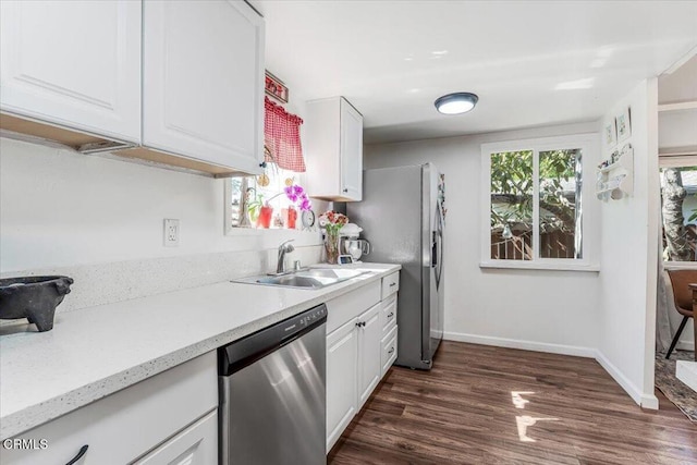 kitchen with dark wood-style flooring, baseboards, a sink, dishwasher, and white cabinets