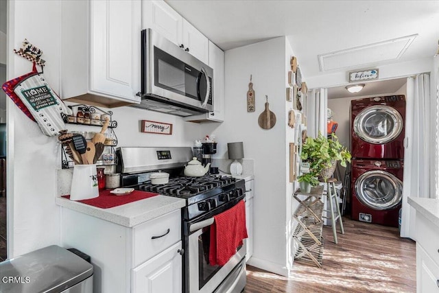 kitchen with stacked washer and clothes dryer, light countertops, stainless steel appliances, and white cabinets