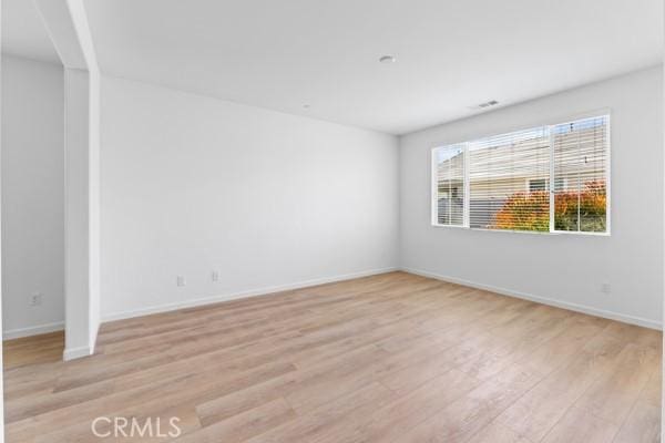 empty room featuring baseboards and light wood finished floors