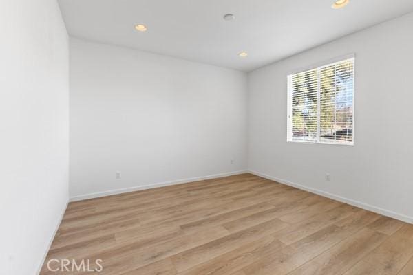 spare room featuring baseboards, recessed lighting, and light wood finished floors