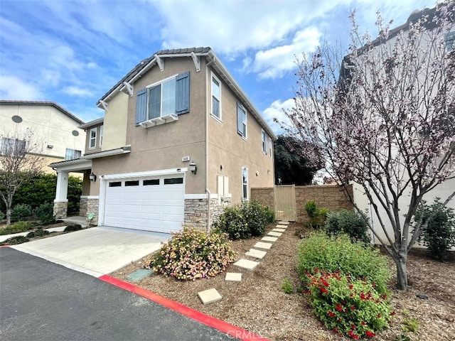 1406 Girona Dr, Pomona, CA 91766 - view of home's exterior featuring stone siding, fence, a garage, concrete driveway, and stucco siding