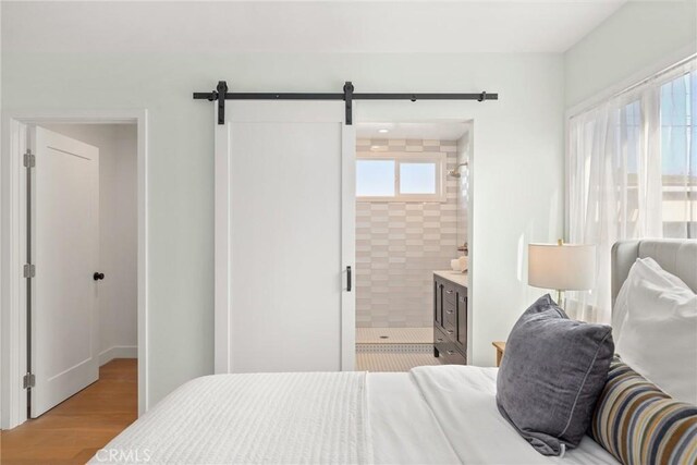 2902 Ladoga Ave, Long Beach, CA 90815 - bedroom featuring a barn door, wood finished floors, and ensuite bathroom