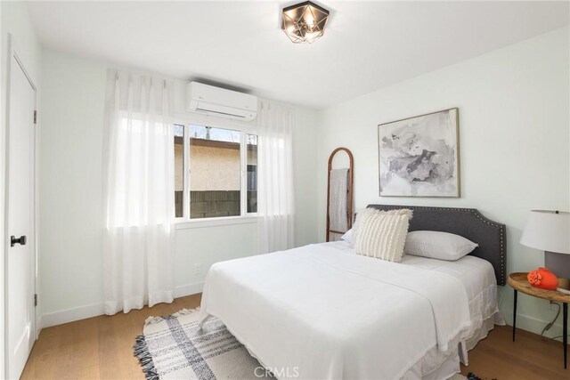 2902 Ladoga Ave, Long Beach, CA 90815 - bedroom with a wall mounted AC, wood finished floors, and baseboards