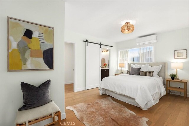 2902 Ladoga Ave, Long Beach, CA 90815 - bedroom featuring a barn door, a wall mounted air conditioner, wood finished floors, and baseboards