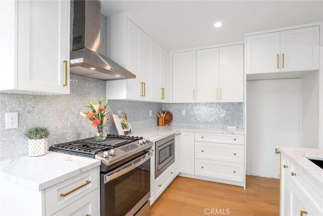 2902 Ladoga Ave, Long Beach, CA 90815 - kitchen featuring appliances with stainless steel finishes, wall chimney exhaust hood, light wood-type flooring, white cabinetry, and recessed lighting