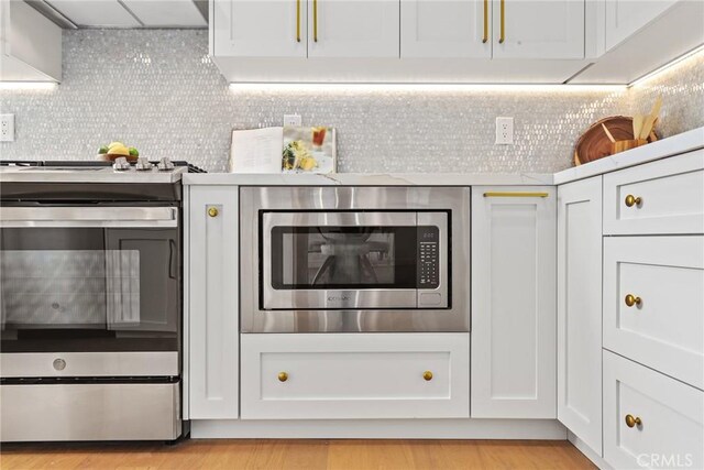 2902 Ladoga Ave, Long Beach, CA 90815 - kitchen with appliances with stainless steel finishes, exhaust hood, white cabinets, and light wood-type flooring