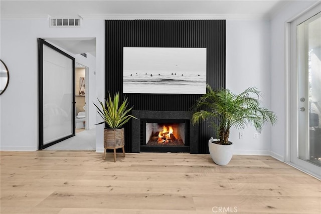 2233 Martin Unit 212, Irvine, CA 92612 - interior details featuring visible vents, crown molding, wood finished floors, baseboards, and a warm lit fireplace