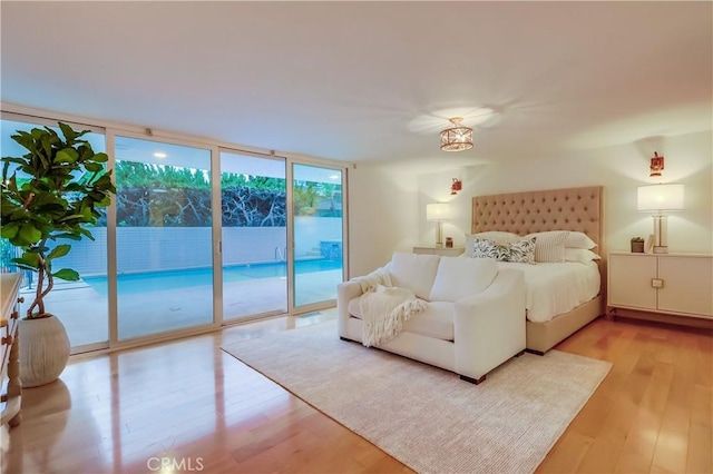 bedroom featuring expansive windows, light wood-type flooring, and access to exterior