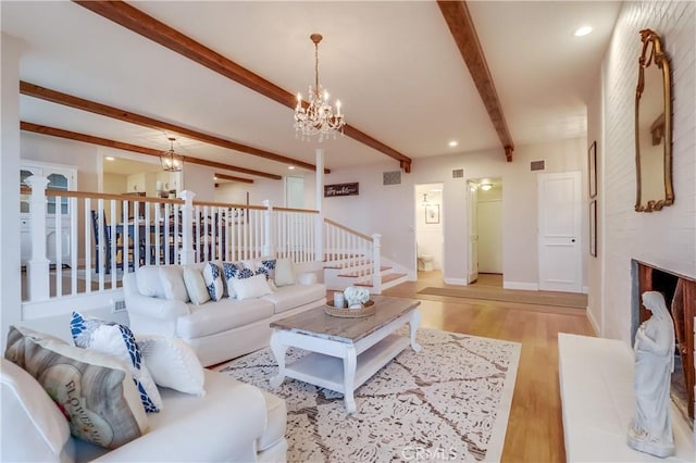 living area with wood finished floors, beam ceiling, baseboards, visible vents, and a notable chandelier