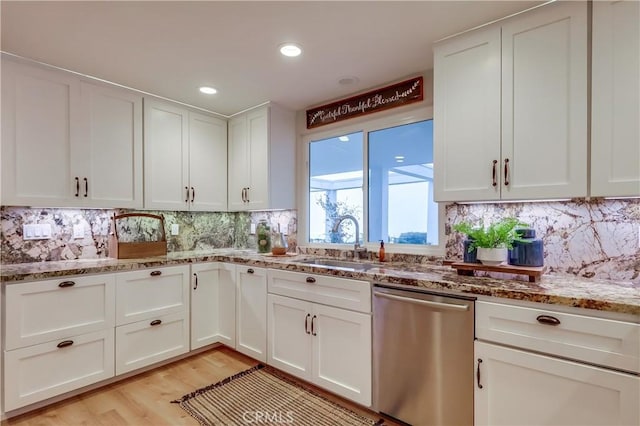 kitchen featuring a sink, stone countertops, white cabinetry, dishwasher, and decorative backsplash