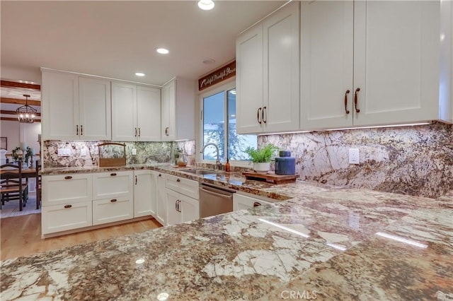 kitchen with white cabinetry, a notable chandelier, light stone counters, and stainless steel dishwasher