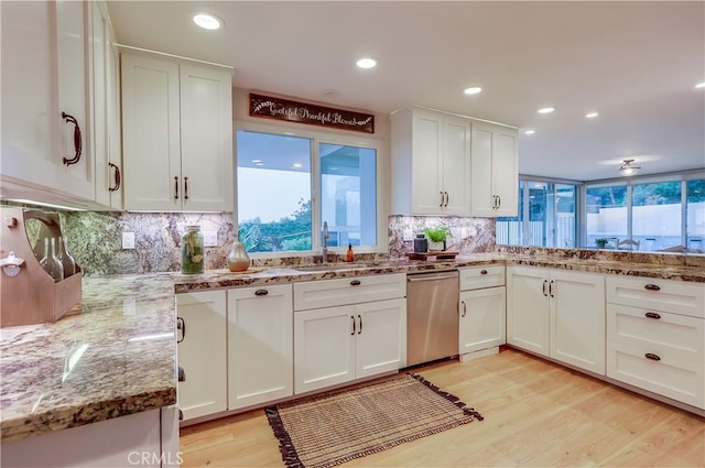 kitchen with light wood finished floors, white cabinets, light stone counters, and dishwasher