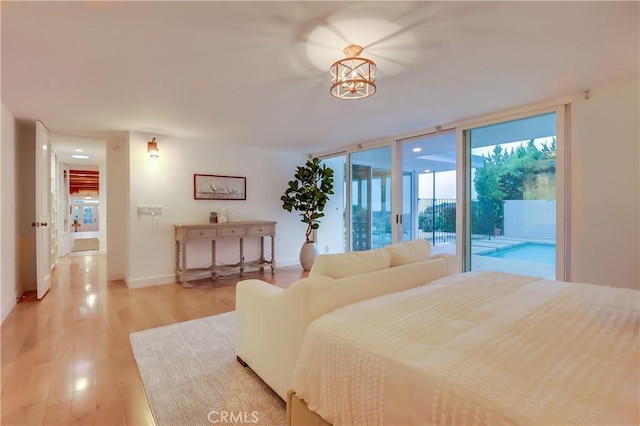 bedroom with baseboards, light wood-type flooring, and access to exterior