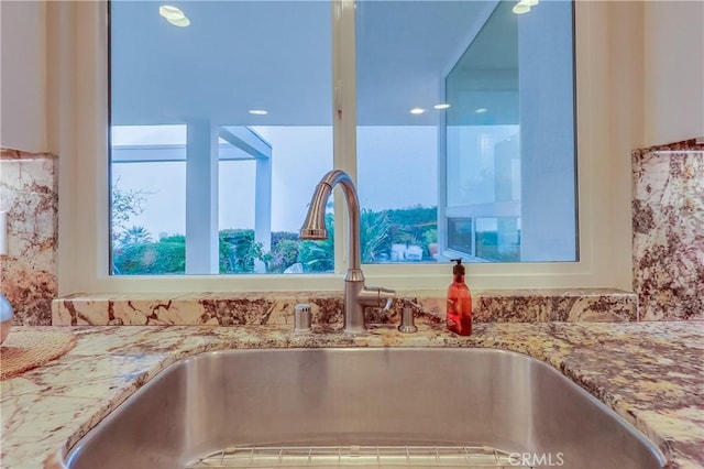 room details featuring light stone counters and a sink