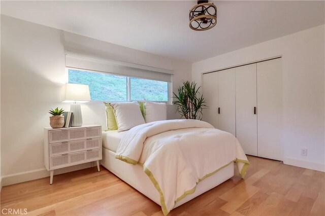 bedroom with light wood-style flooring, a closet, and baseboards