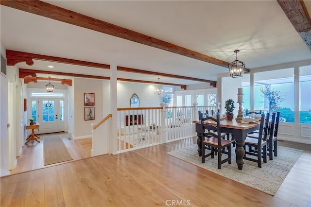 dining room featuring baseboards, beamed ceiling, a chandelier, and wood finished floors