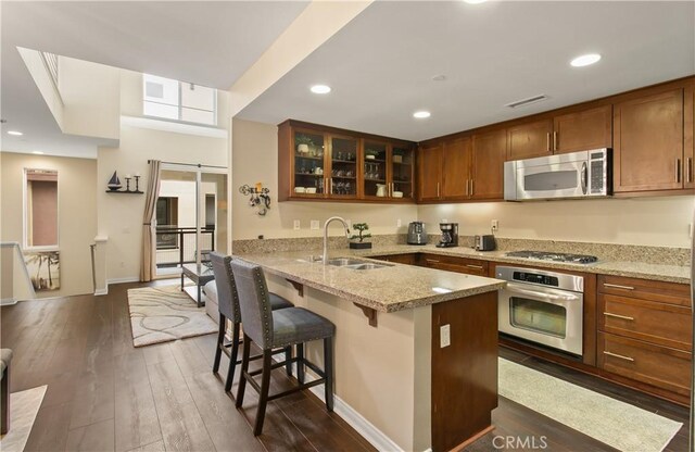 615 Rockefeller, Irvine, CA 92612 - kitchen featuring stainless steel appliances, a breakfast bar, a peninsula, glass insert cabinets, and dark wood finished floors