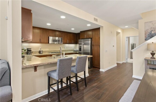 615 Rockefeller, Irvine, CA 92612 - kitchen with appliances with stainless steel finishes, a peninsula, dark wood-style floors, light stone countertops, and recessed lighting