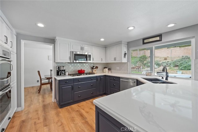 710 W Country Hills Dr W, La Habra, CA 90631 - kitchen featuring light wood-style floors, white cabinets, a sink, gray cabinetry, and stainless steel appliances