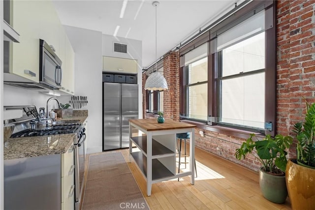 460 S Spring St Unit 302, Los Angeles, CA 90013 - kitchen with stainless steel appliances, visible vents, brick wall, wooden counters, and light wood-style floors