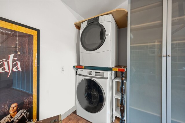 3569 Kelton Ave, Los Angeles, CA 90034 - laundry area featuring stacked washer and clothes dryer, wood finished floors, and baseboards