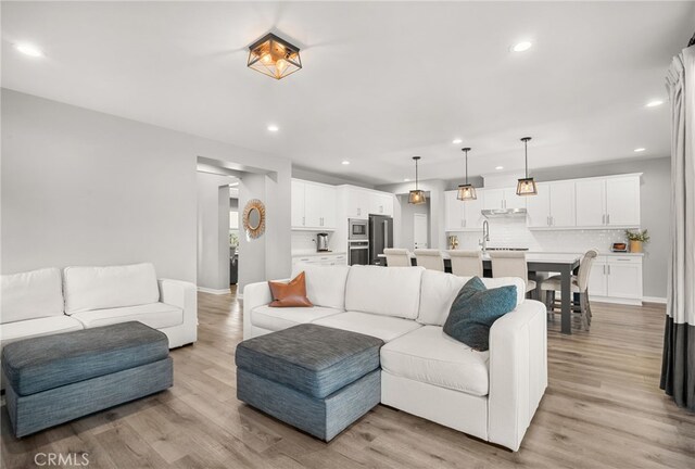 living area with baseboards, recessed lighting, and light wood finished floors