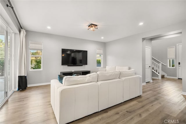 living area featuring recessed lighting, baseboards, stairs, and light wood-type flooring