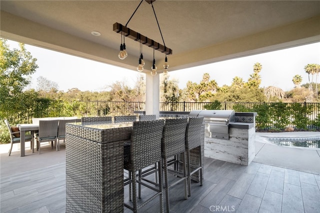 view of patio featuring fence, exterior kitchen, outdoor dining area, outdoor wet bar, and area for grilling
