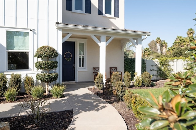 property entrance featuring fence, stucco siding, and a porch