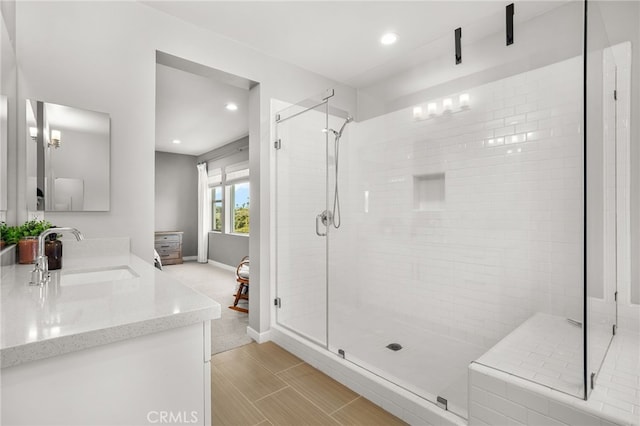 bathroom featuring double vanity, a sink, baseboards, and a shower stall