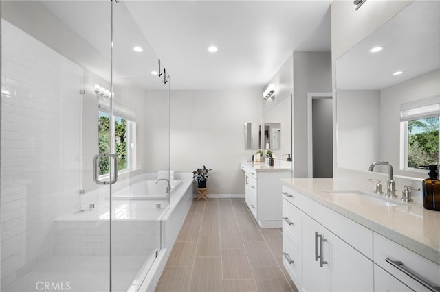 full bathroom featuring recessed lighting, a shower stall, a sink, two vanities, and a bath