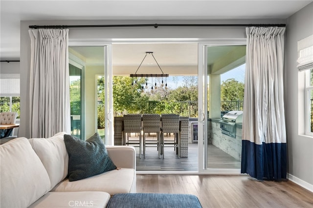 doorway to outside featuring an inviting chandelier, baseboards, and wood finished floors