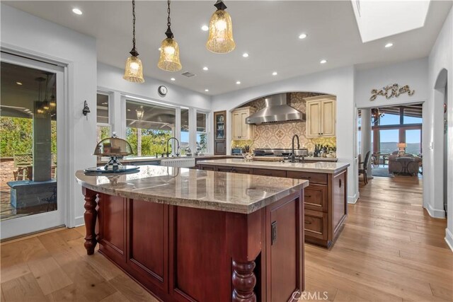 23815 Park Belmonte, Calabasas, CA 91302 - kitchen featuring wall chimney exhaust hood, a center island with sink, healthy amount of natural light, decorative backsplash, and recessed lighting