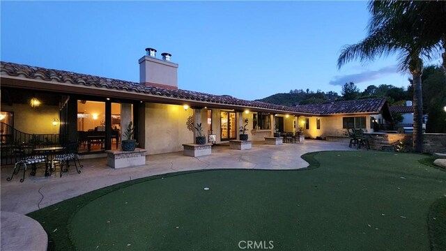 23815 Park Belmonte, Calabasas, CA 91302 - back of property with a putting area, a patio, a chimney, stucco siding, and a tile roof