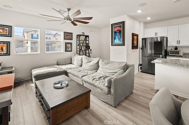 living room with a ceiling fan, recessed lighting, baseboards, and light wood-type flooring