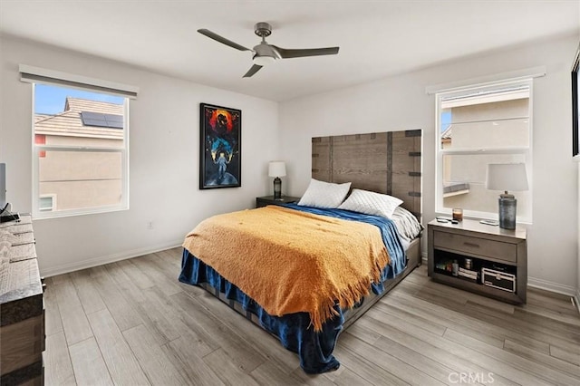 bedroom featuring baseboards, wood finished floors, and a ceiling fan
