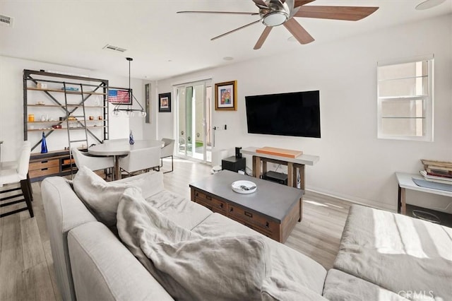 living area with baseboards, visible vents, wood finished floors, and ceiling fan