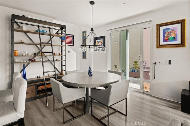 dining space with baseboards, light wood-style floors, and a notable chandelier